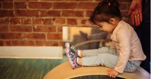 A Roots student balances on a rocker board